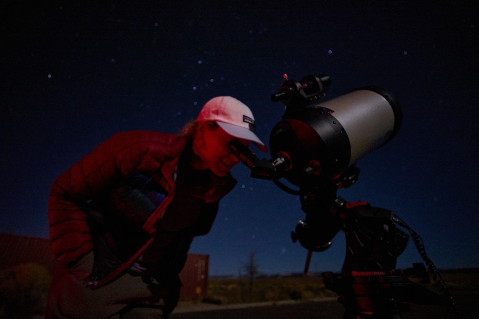 Guest wearing a red headlamp looking through a Celestron telescope at night near Bryce Canyon